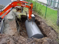 Kubota-graafmachine die een horizontale opslagtank laat zakken in een uitgegraven kuil